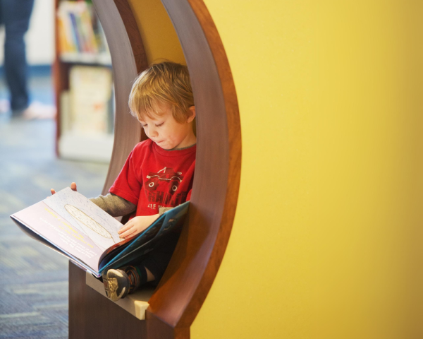 Young child reading a picture book in the children's section at the Eastside branch